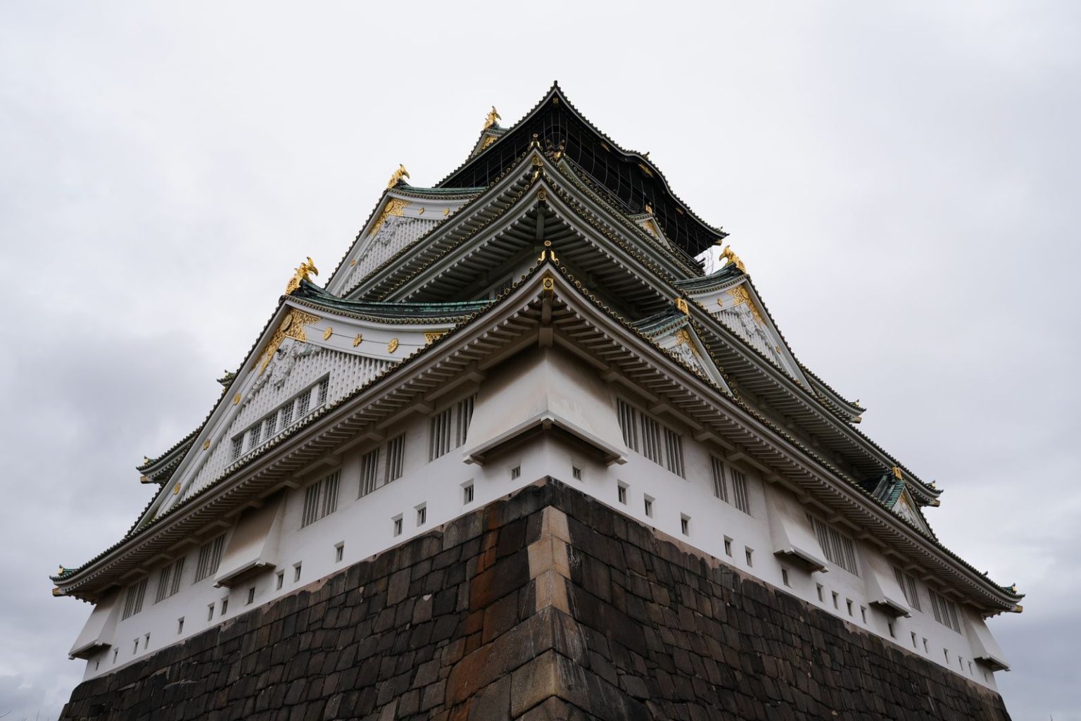 Before You Rip Out The Kitchen, Book Osaka: The Holidays To Take Before Renovating Your Home Osaka Castle in Japan viewed from below against a cloudy sky