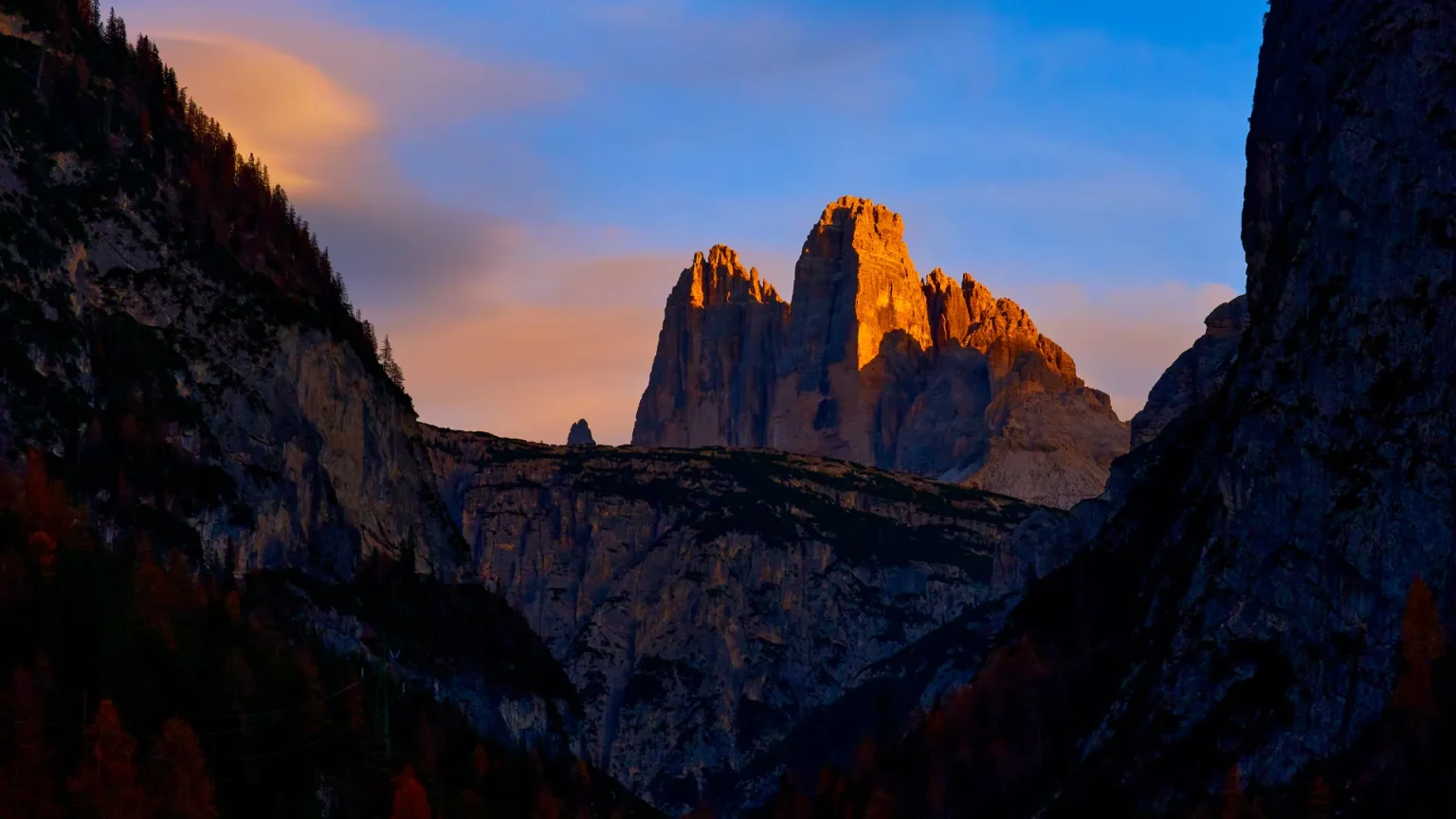 Dolomite peaks glowing at sunrise above a forested valley